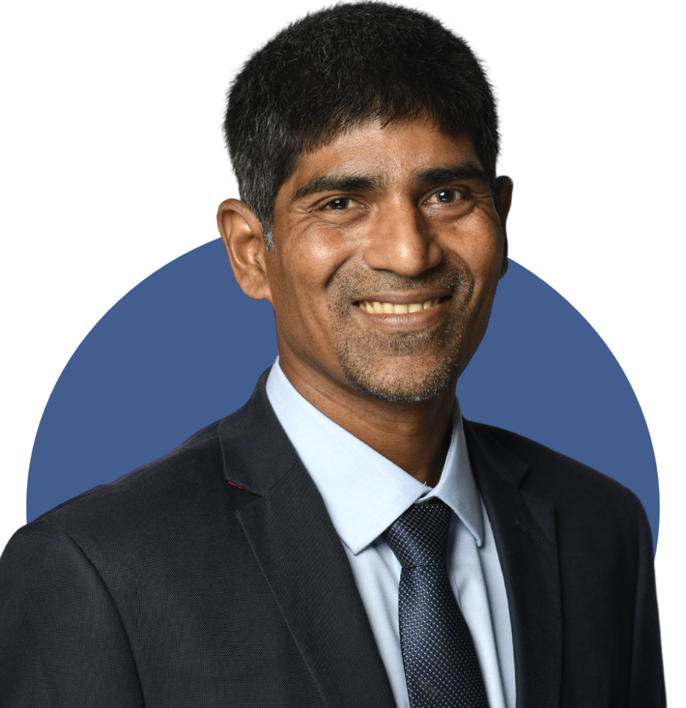 Professional headshot of a man in formal attire smiling confidently against a blue background