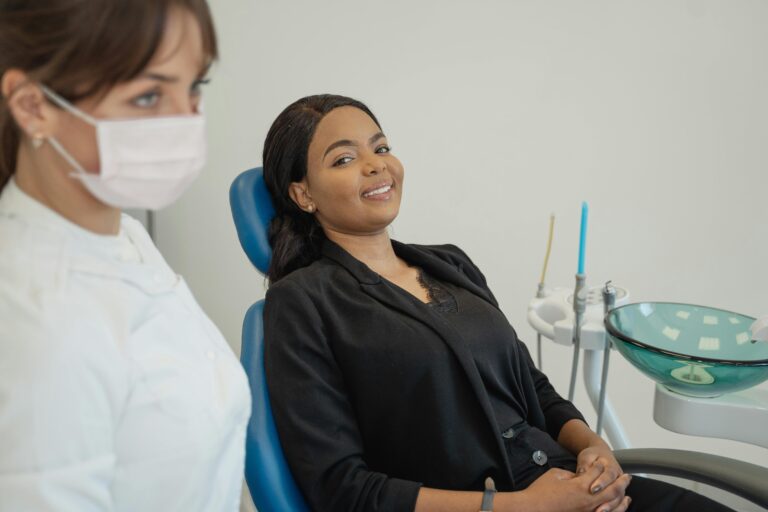 Smiling patient sitting in a dental chair while a dentist stands nearby during a checkup