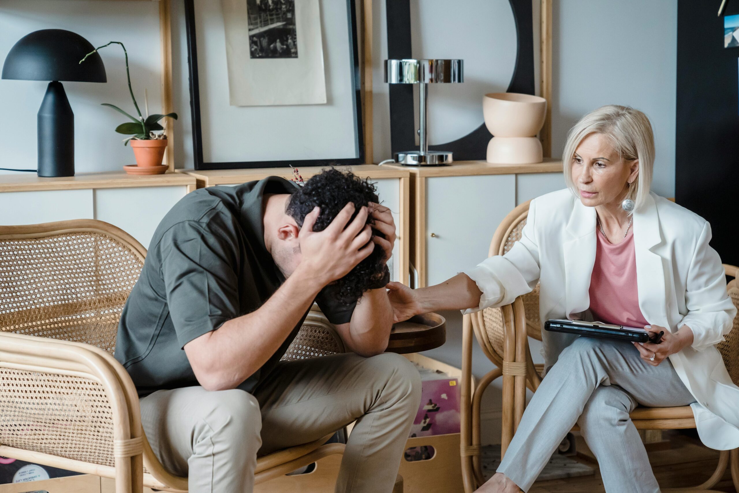 A therapist offering emotional support to a distressed patient in a comfortable therapy setting